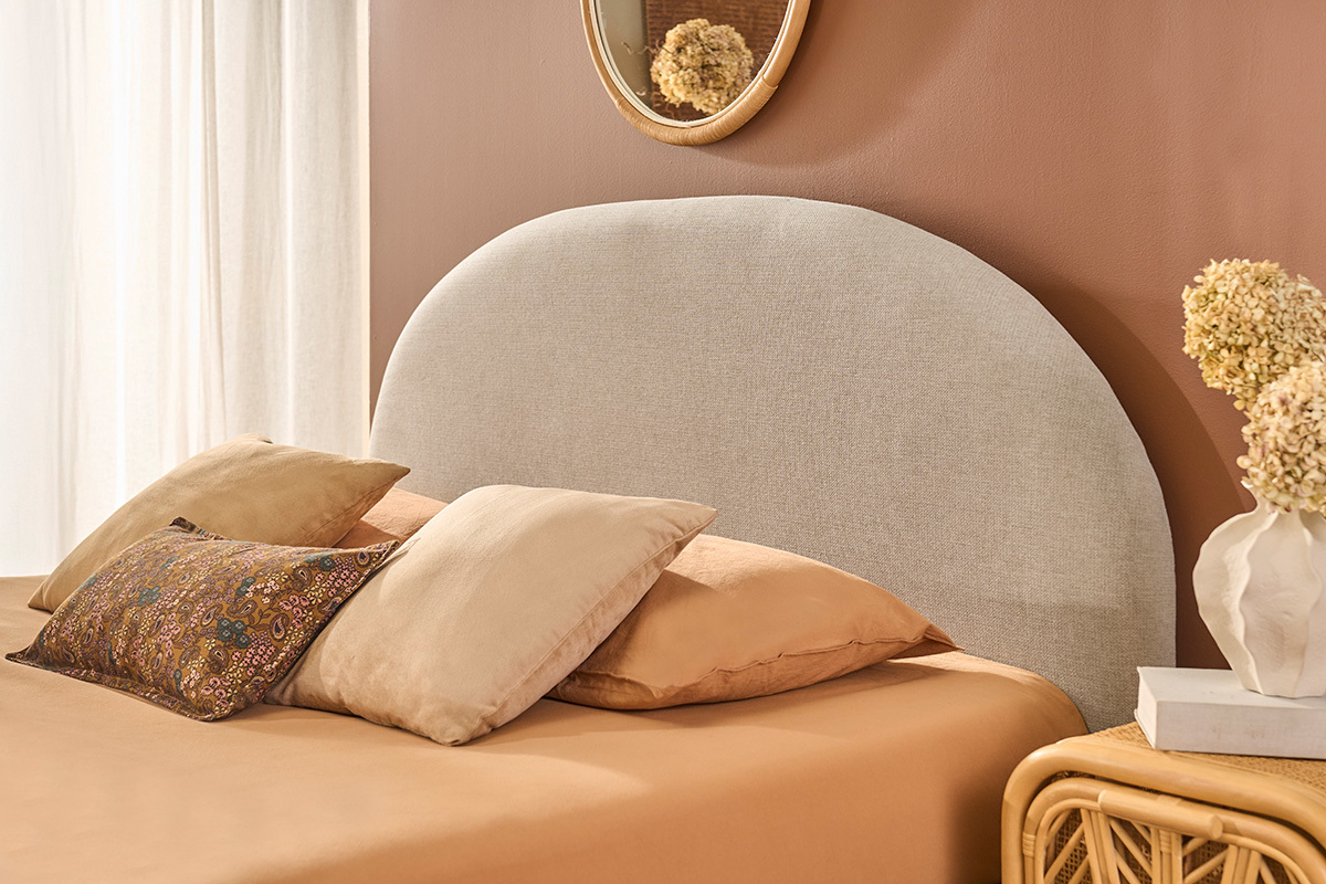 Lit coffre tissu beige avec coussins, miroir rond au mur, vue zoom�e