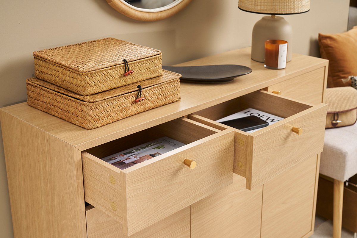 Meuble d'entre en bois clair avec tiroirs ouverts et objets dessus, vue de 3/4.