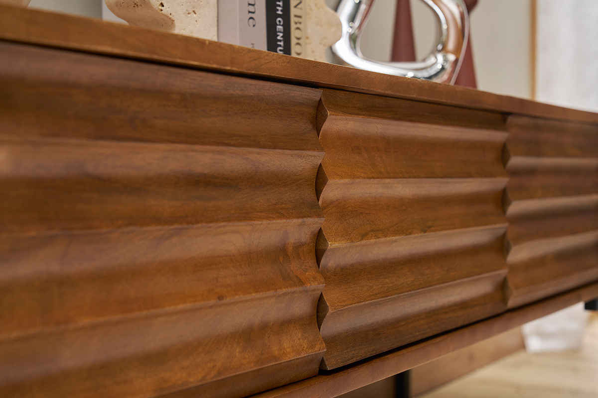 Gros plan sur le meuble TV ONDA en bois de manguier massif avec motifs sculpts.