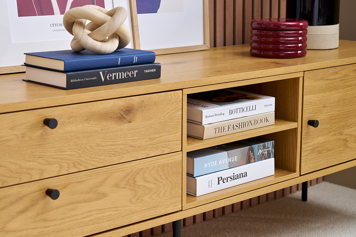 Meuble TV zoom en bois clair avec livres et objets dcoratifs sur le dessus.