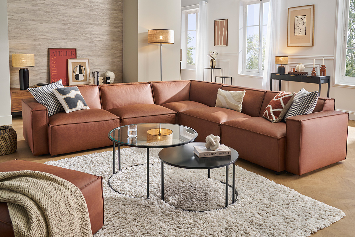 Salon avec canap en cuir marron et tables basses sur un tapis blanc.