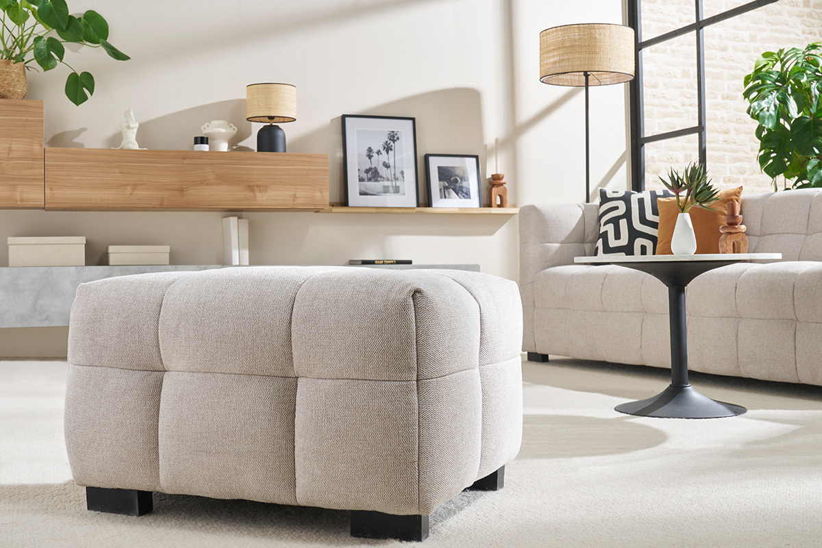 Salon moderne avec pouf en tissu beige, table ronde noire et canap� assorti.