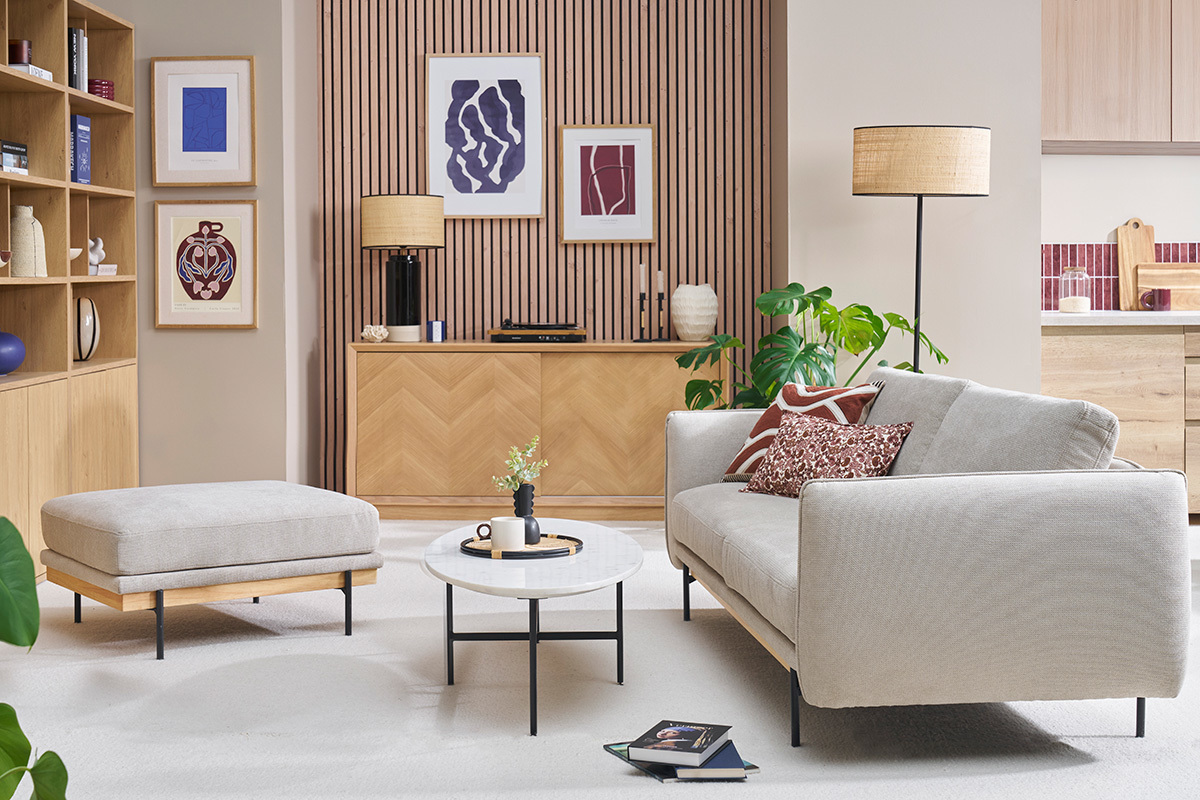 Salon avec pouf repose-pieds en tissu chenille beige, table basse ronde et canap.