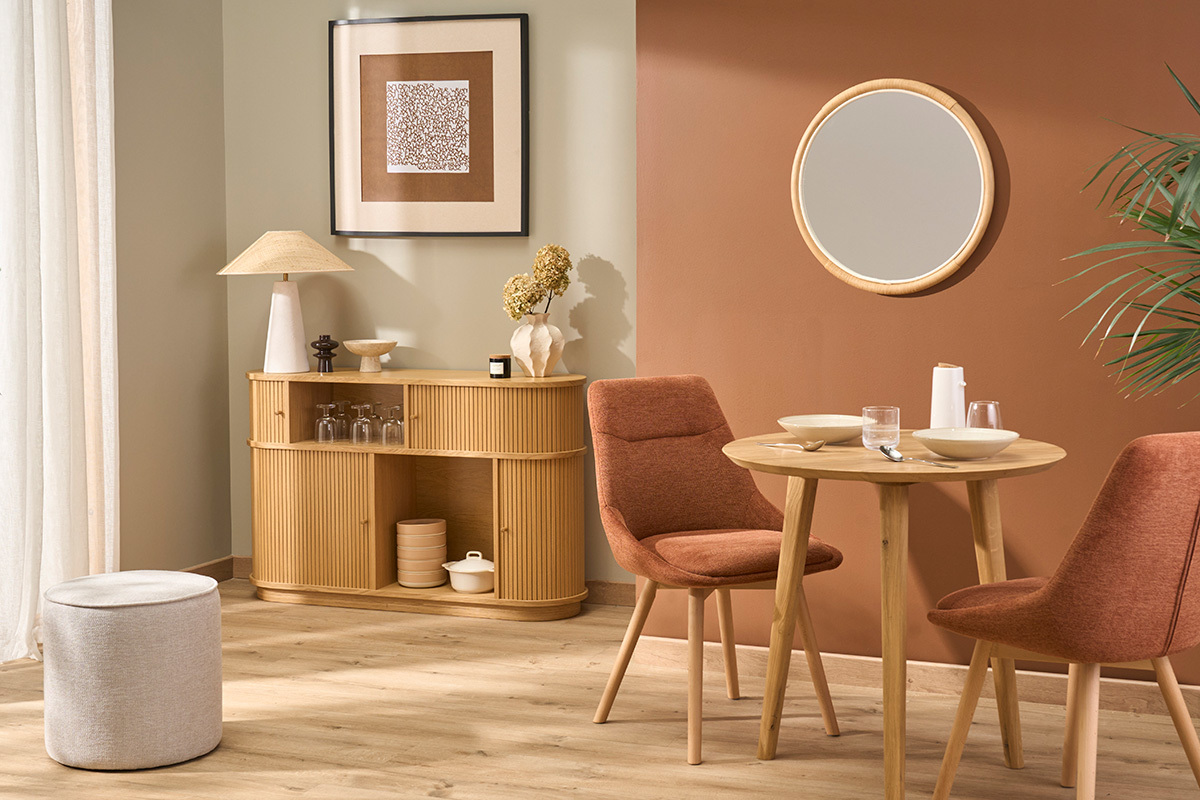 Int�rieur avec pouf rond beige effet velours, meuble en bois, table ronde et chaises.