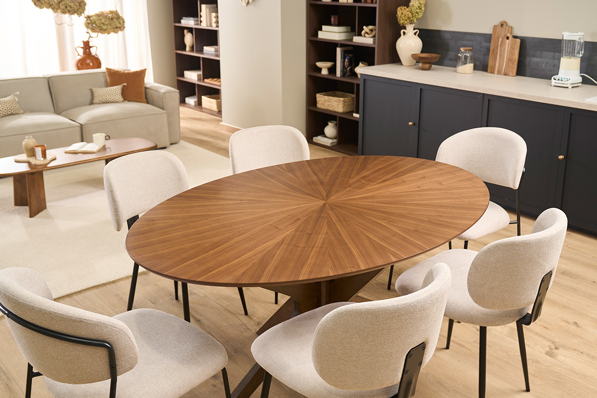 Table � manger ovale en noyer avec pieds sculpturaux, entour�e de chaises beige.