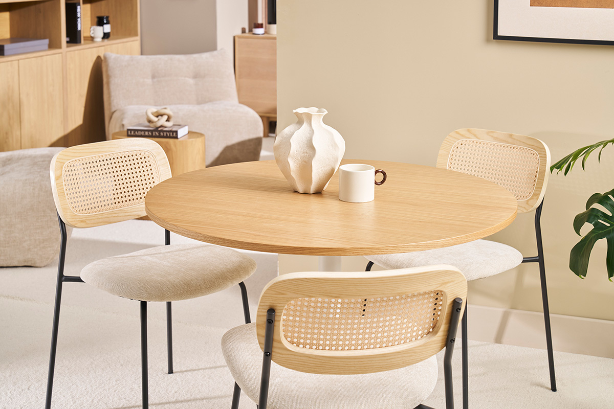 Table ronde en bois avec chaises en rotin, vase blanc et tasse, ambiance intrieure moderne.