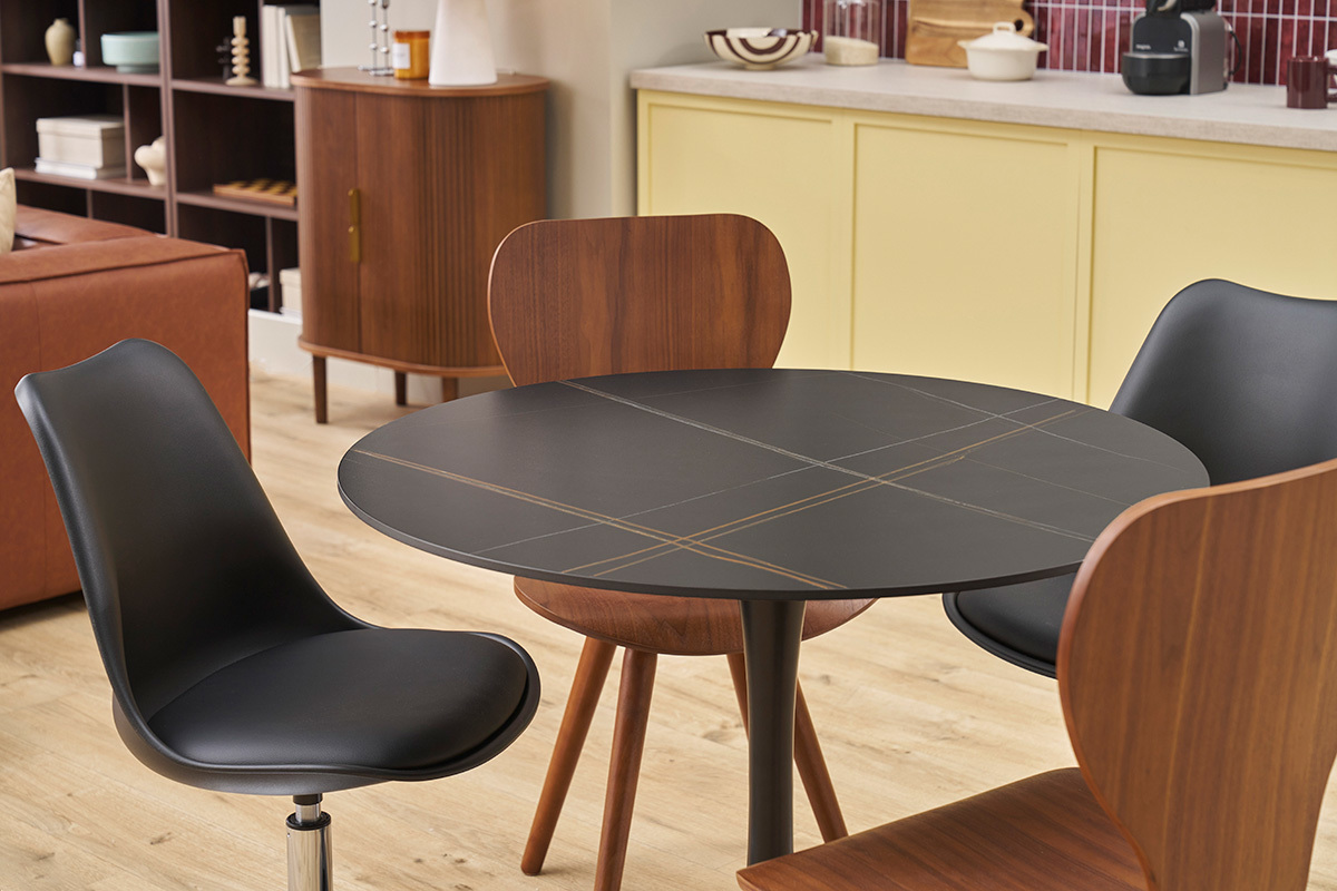 Table ronde en cramique noire et mtal avec des chaises, vue d'ensemble dans un intrieur.