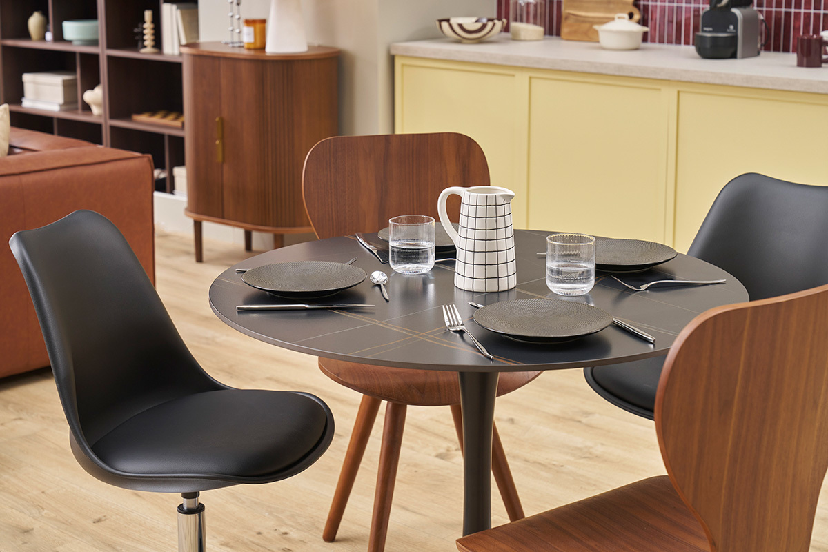 Table ronde en cramique noire et mtal avec couverts, vue de dessus.