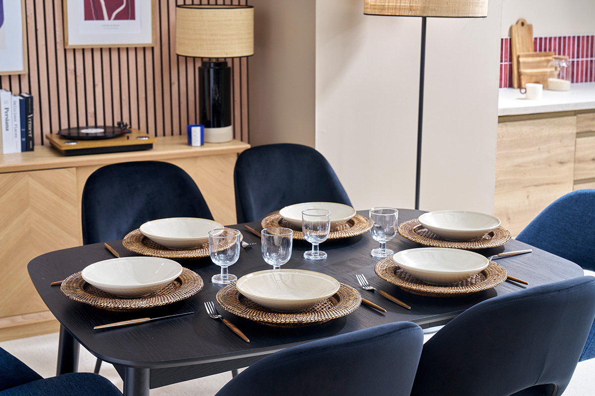 Table  manger noire NORDECO dresse avec assiettes et verres, vue de dessus.