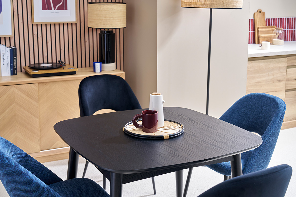 Table  manger noire extensible NORDECO avec chaises bleues, vue d'angle.