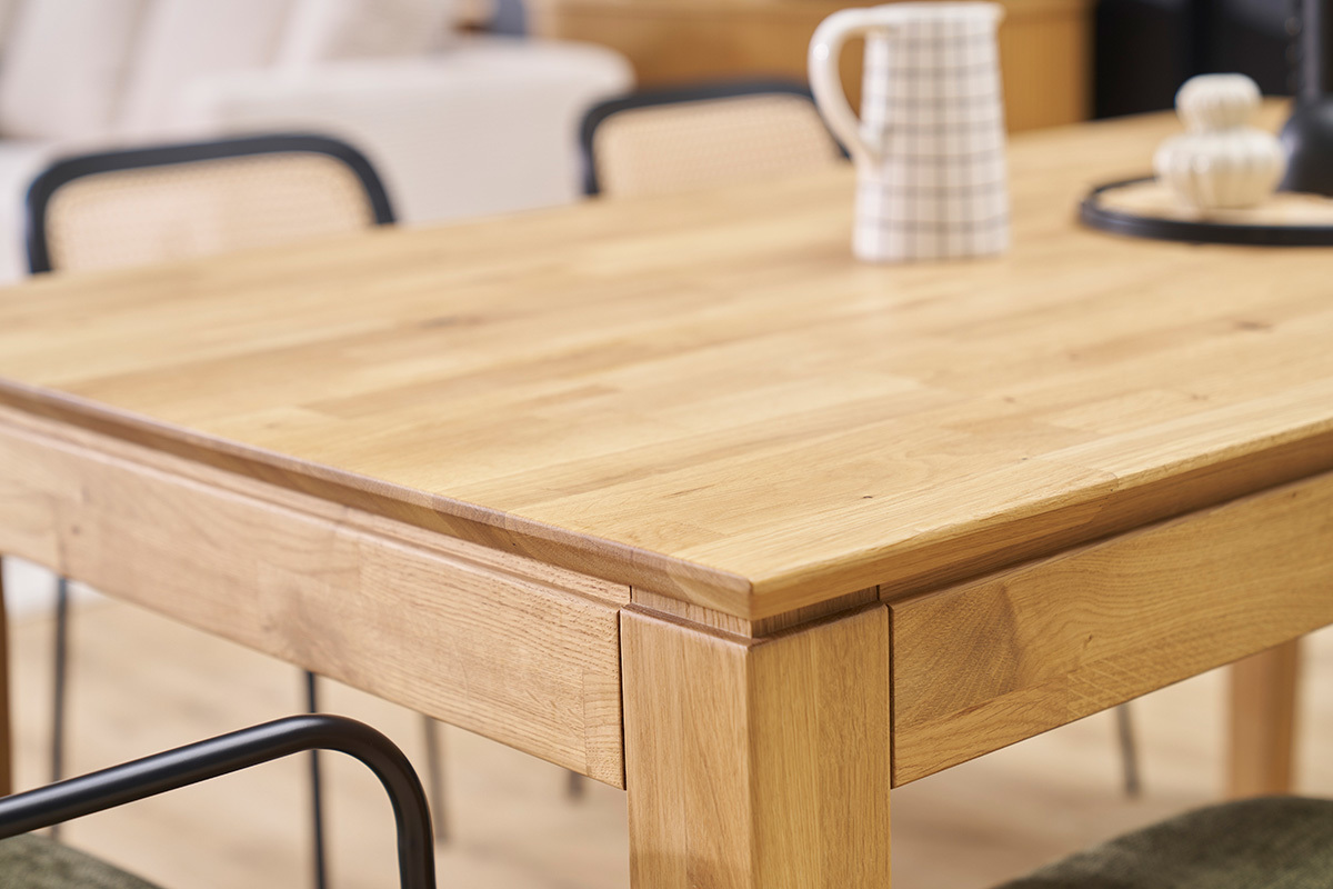 Table  manger extensible en bois clair, vue de ct avec objets poss dessus.