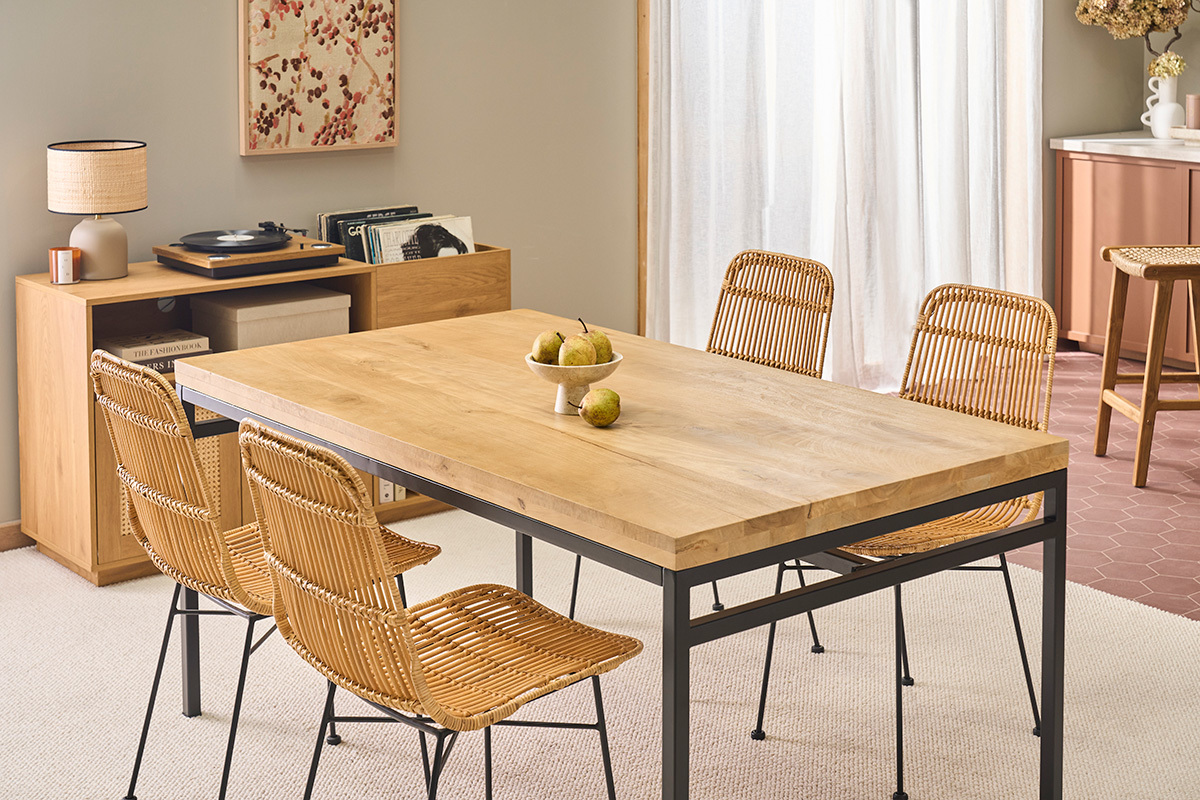 Table � manger industrielle en bois et m�tal avec chaises en rotin, vue d'angle.