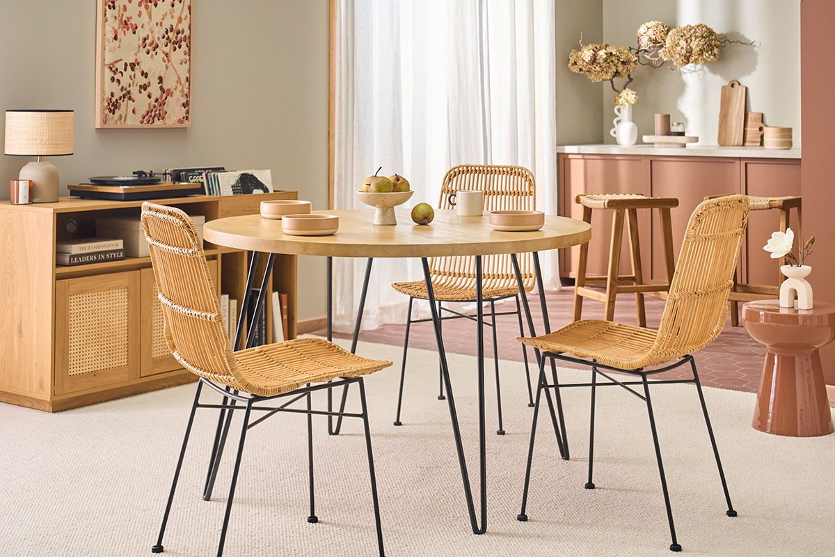 Table ronde en bois avec pi�tement en m�tal, entour�e de chaises osier, dans un int�rieur moderne.