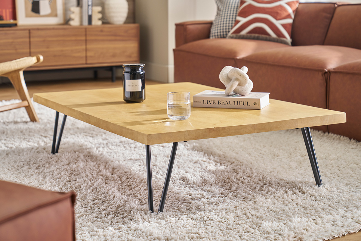 Table basse rectangulaire en bois de manguier sur tapis, vue de ct avec objets dcoratifs.