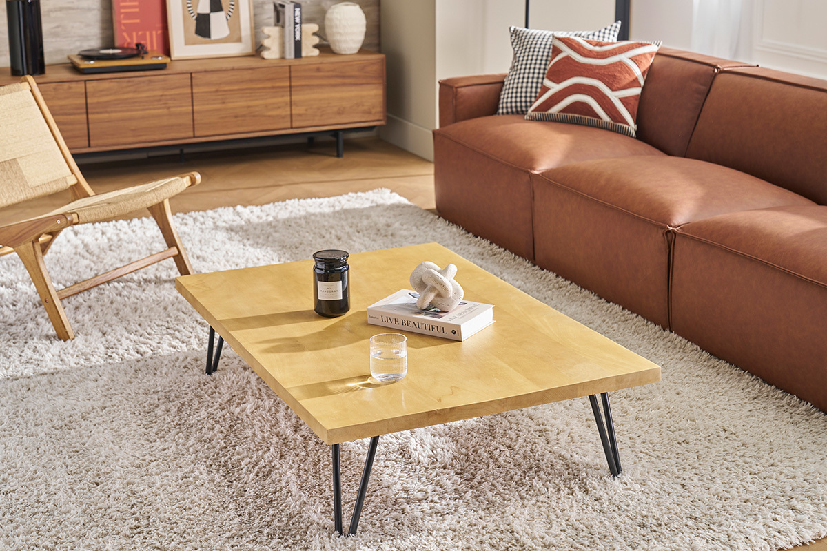 Table basse VIBES en bois de manguier et mtal, vue de trois-quarts, dans un salon avec canap et fauteuil.