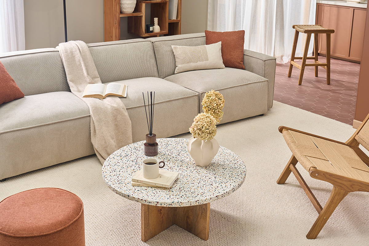 Table basse ronde NESSA en terrazzo et bois de manguier dans un salon moderne.