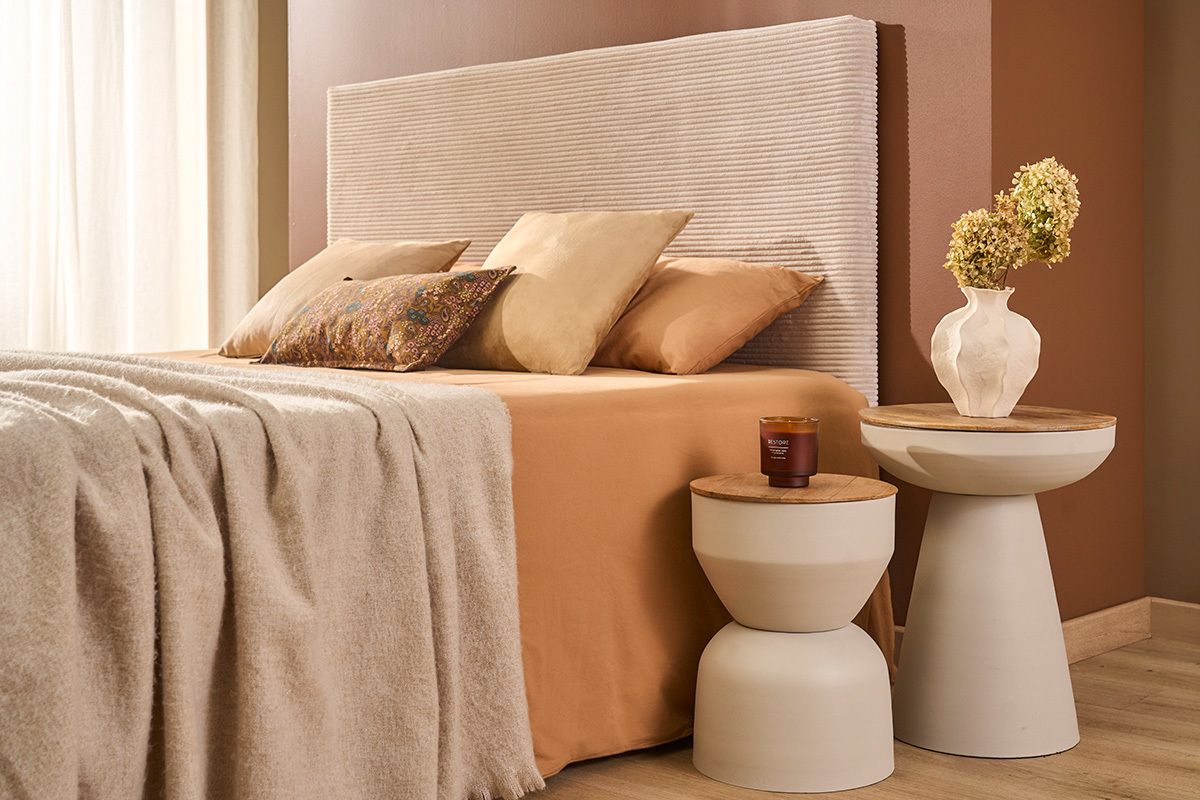 Tables d'appoint YOYO en m�tal gr�ge et bois manguier, pr�s d'un lit avec d�corations.