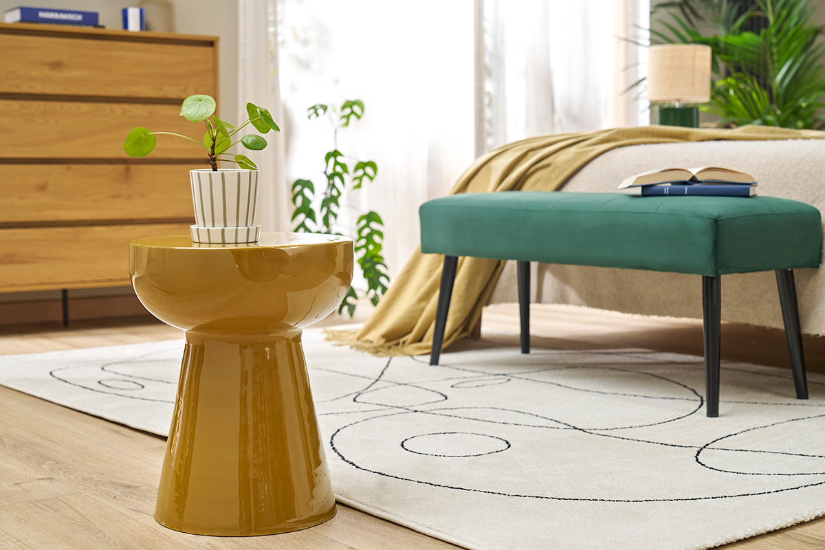 Table d'appoint ronde en m�tal �maill� bronze avec plante vue de face dans une chambre.