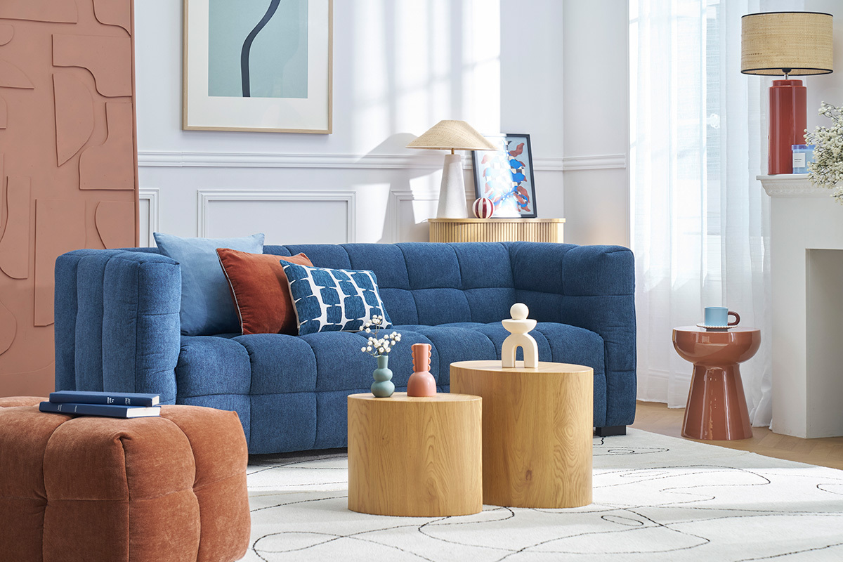 Salon avec canap� bleu, coussins color�s, table d'appoint ronde terracotta sur la droite.