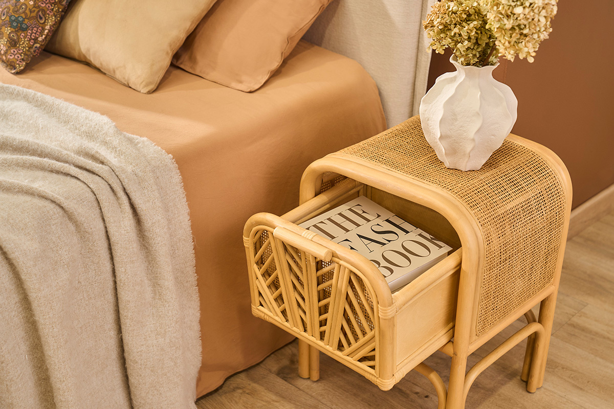 Table de chevet en rotin GALON avec tiroir ouvert contenant un livre, vue d'angle.