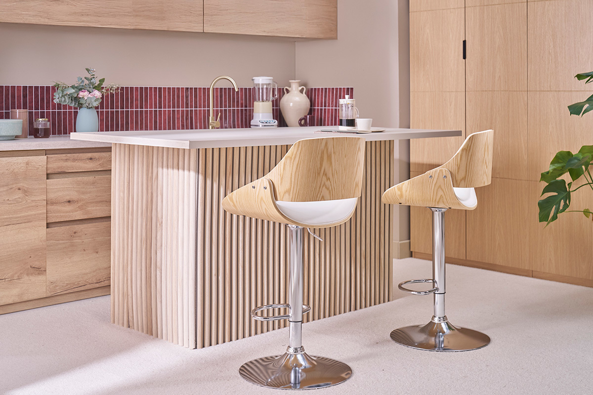 Deux tabourets de bar blancs et bois clair CLASH, r�glables et pivotants, devant un �lot de cuisine en bois.