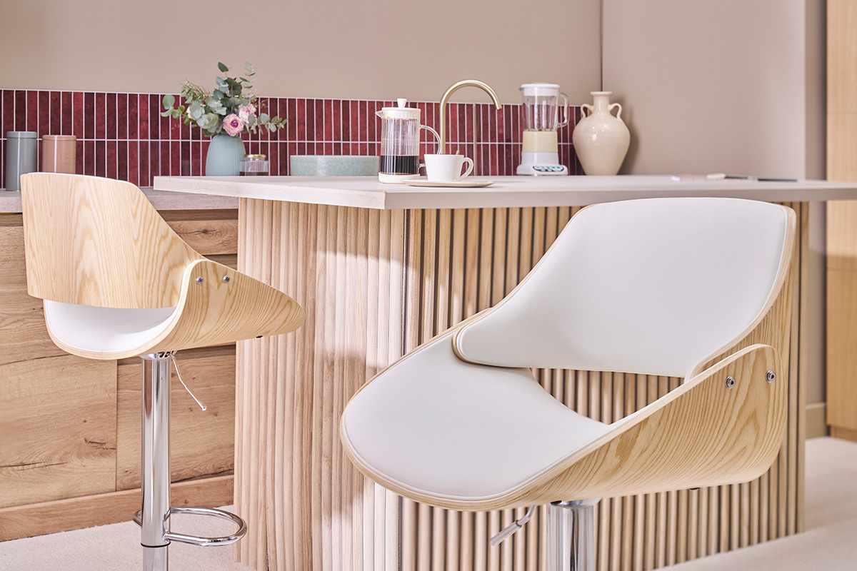 Deux tabourets de bar CLASH, design blanc et bois clair, devant un comptoir de cuisine.
