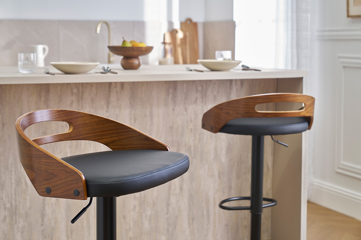 Deux tabourets de bar MANO en bois de noyer et cuir noir devant un comptoir de cuisine.