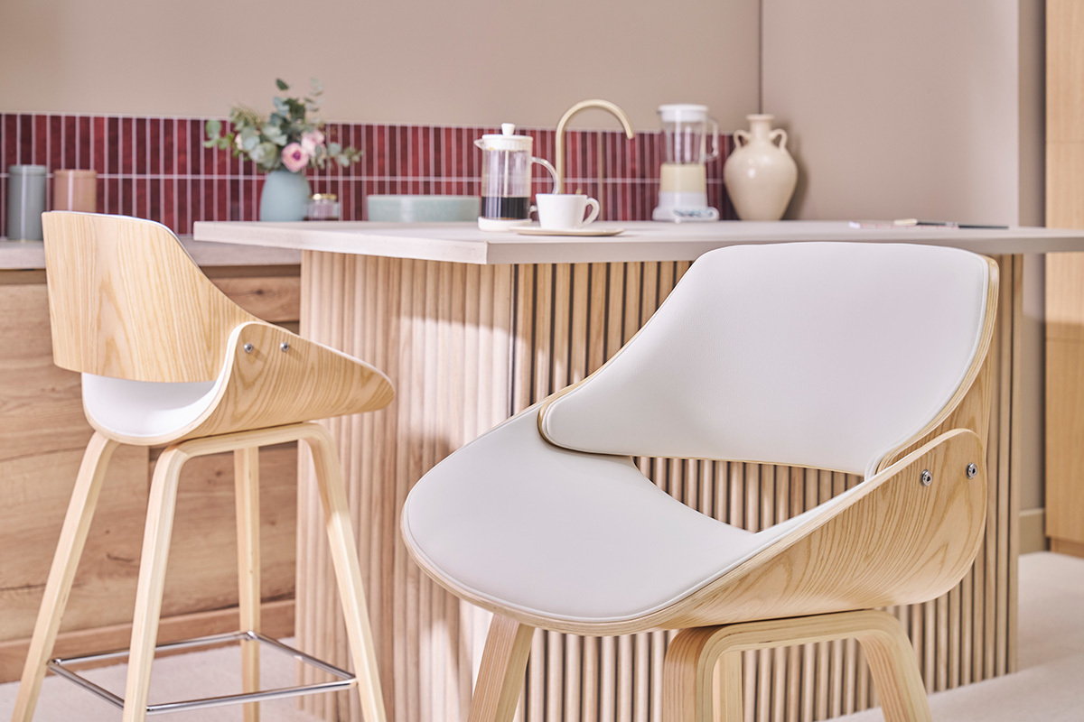 Tabourets de bar blancs et bois clair CLASH devant un comptoir de cuisine.