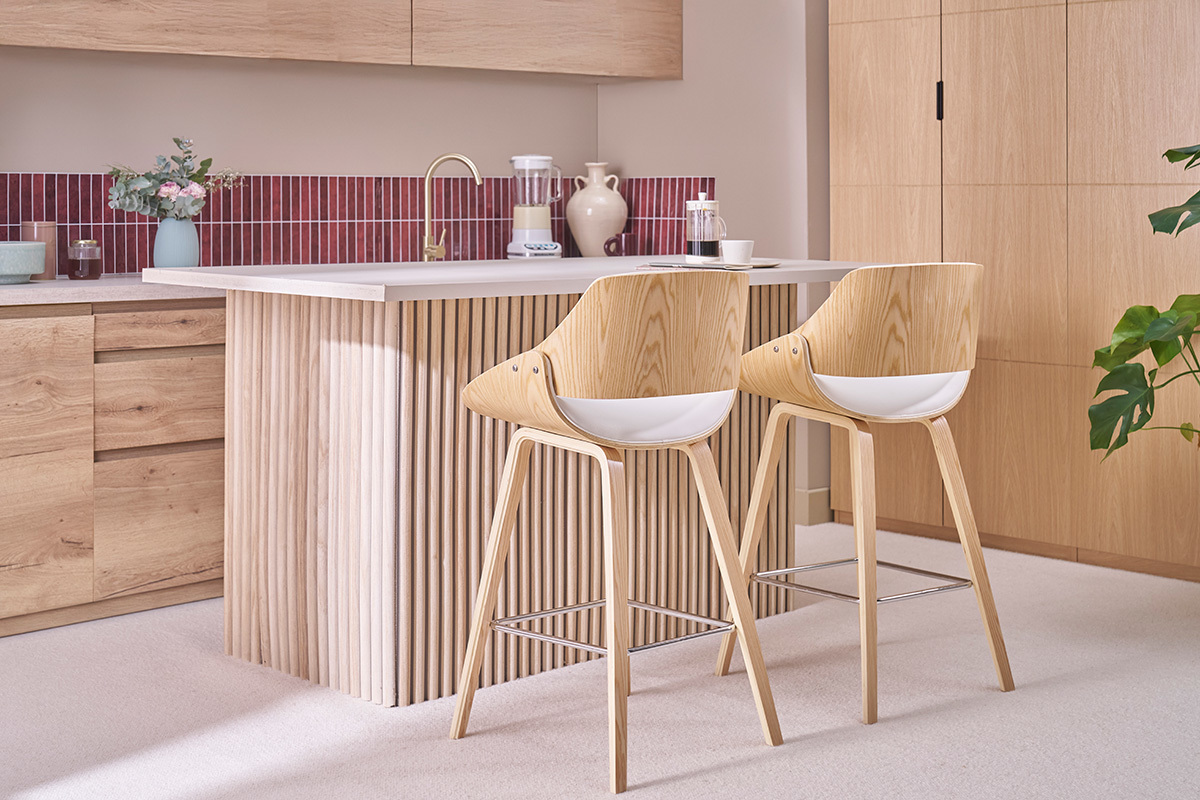 Deux tabourets de bar en bois clair et blanc devant un �lot de cuisine moderne.