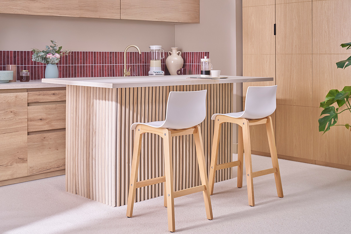 Deux tabourets de bar en bois et blanc, avec dossier, plac�s devant un �lot central en cuisine.