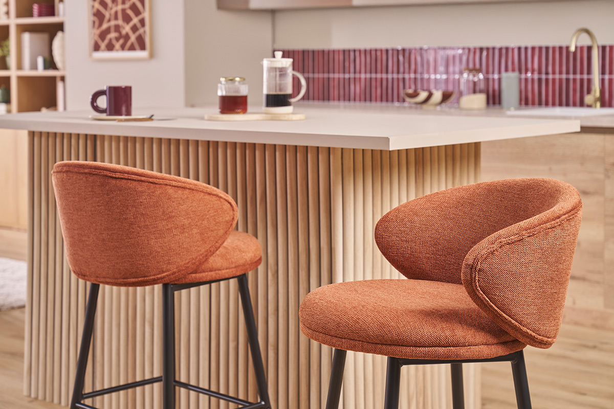 Deux tabourets de bar en tissu terre br�l�e avec pieds m�talliques noirs devant un �lot de cuisine.