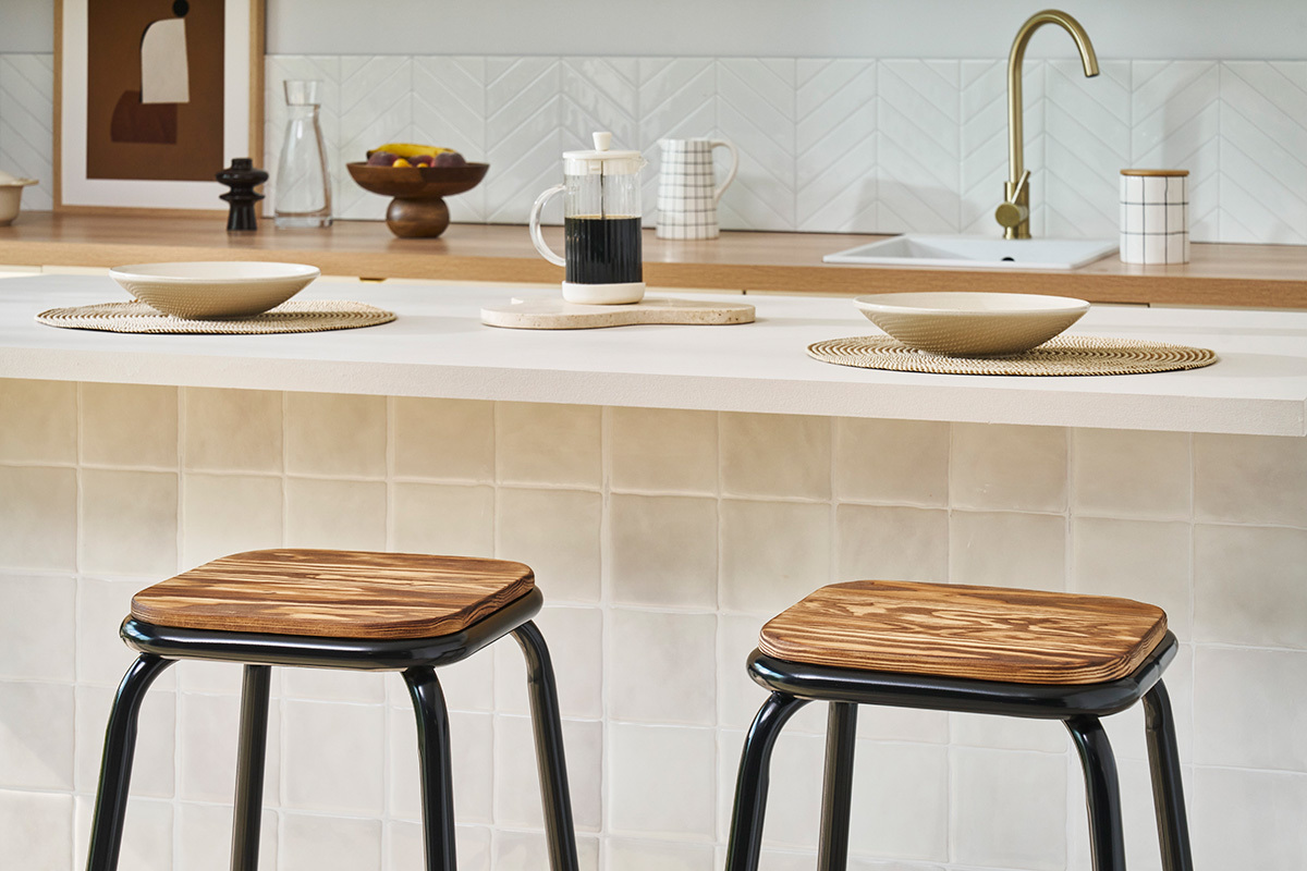 Tabourets de bar noir et bois fonc devant un comptoir cuisine.