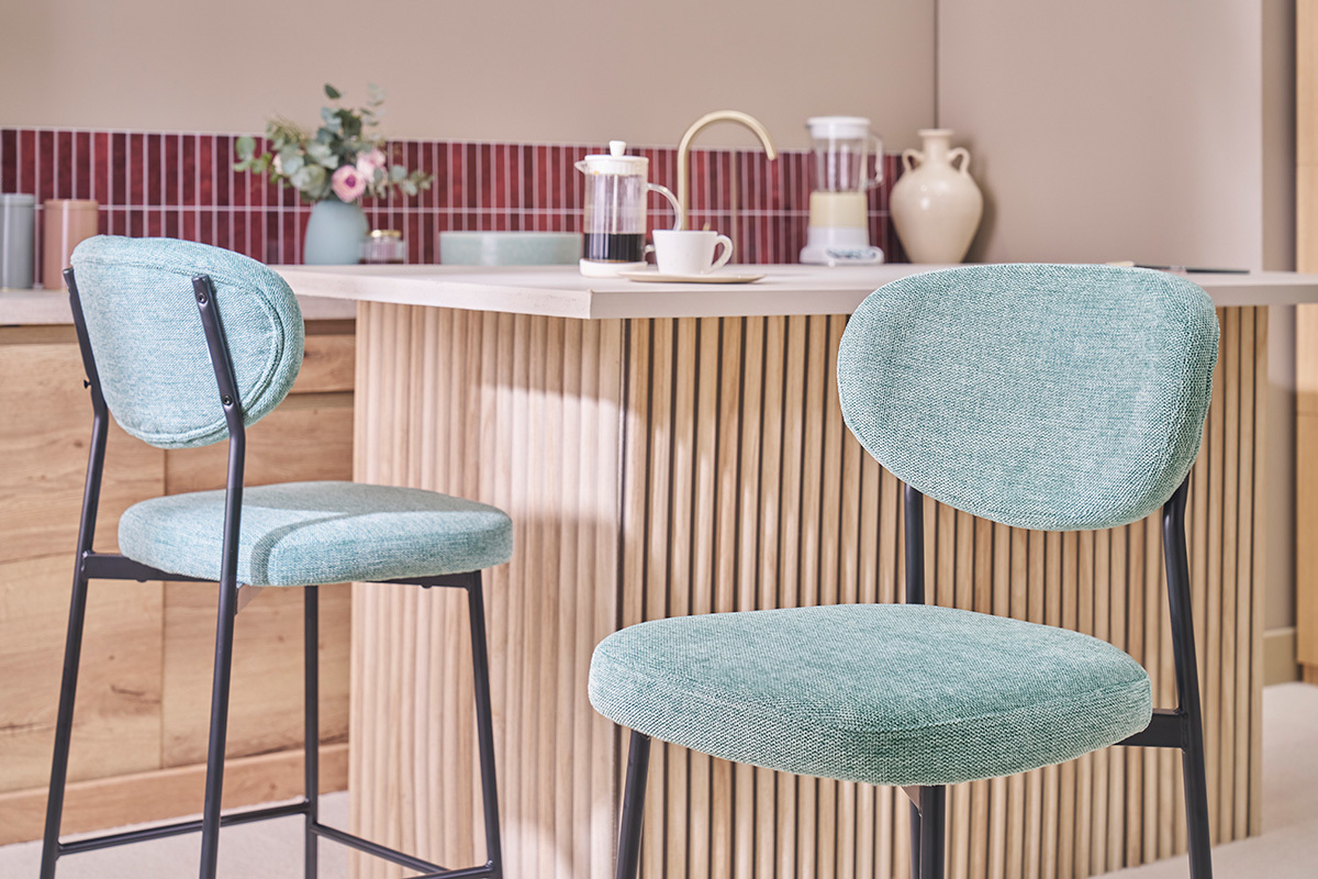 Deux tabourets de bar en tissu c�ladon et m�tal noir devant un �lot de cuisine.