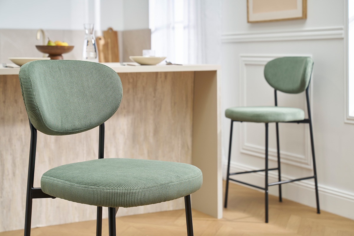 Tabourets de bar vert kaki en velours avec pieds en mtal noir devant un lot de cuisine.