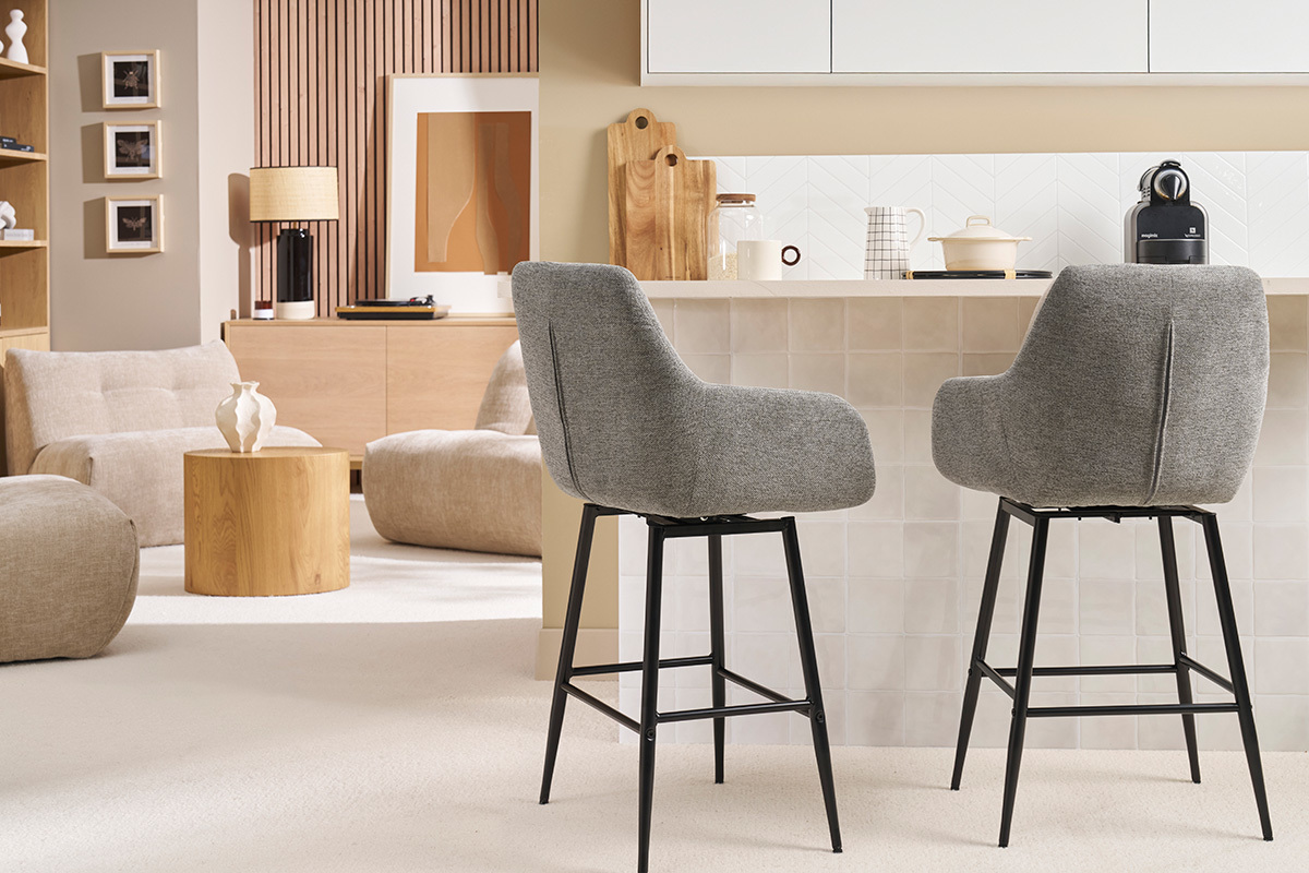 Deux tabourets de bar gris devant un comptoir dans un salon moderne.