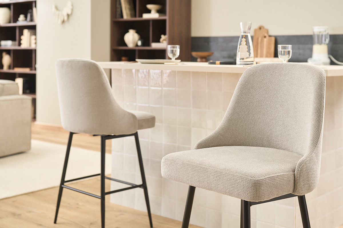Deux tabourets de bar pivotants en tissu beige et m�tal noir devant un comptoir de cuisine.