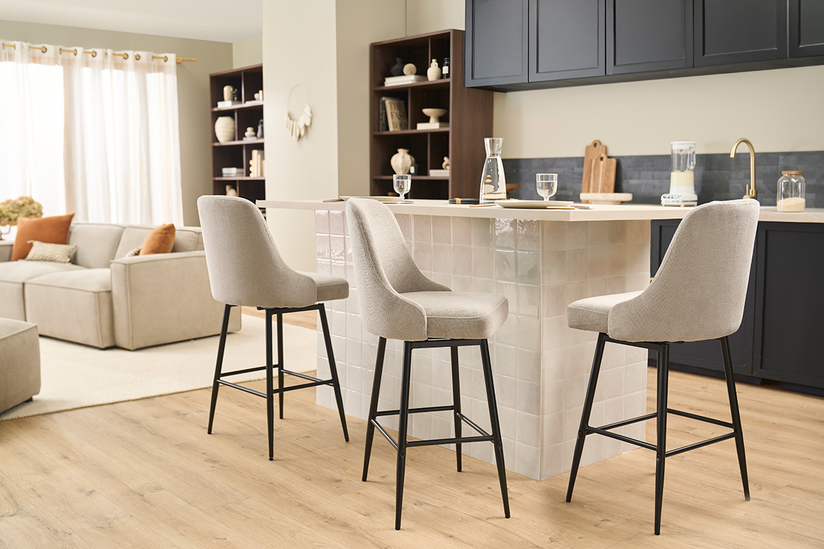 Tabourets de bar pivotants beige avec pieds en m�tal noir, autour d'un �lot de cuisine moderne.