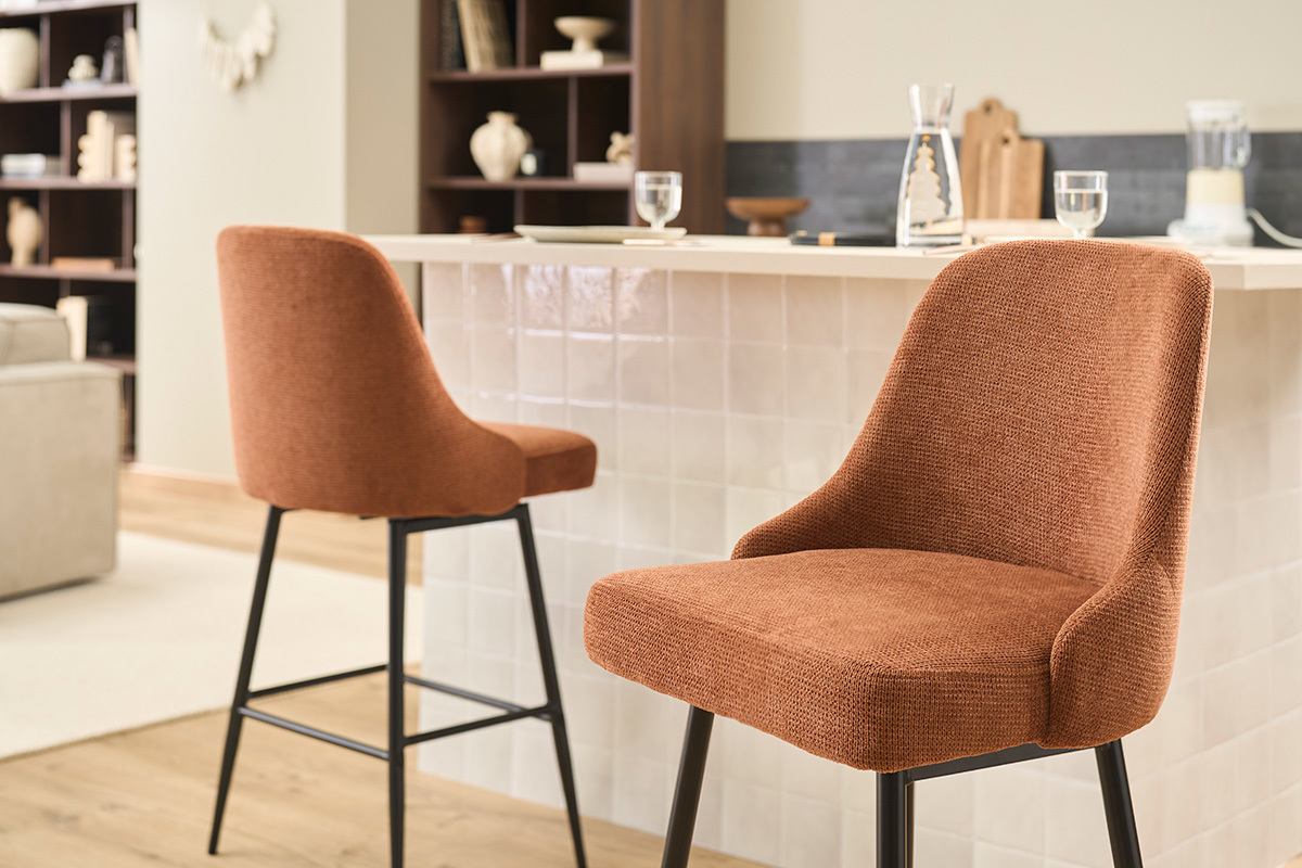 Tabourets de bar en tissu terre br�l�e et m�tal noir devant un comptoir.