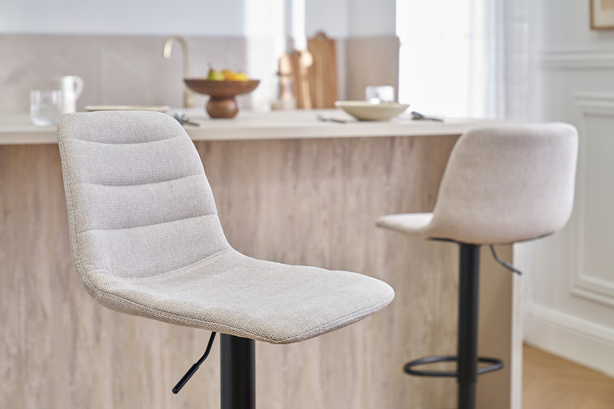 Tabourets de bar rglables en tissu beige et mtal noir devant un comptoir.