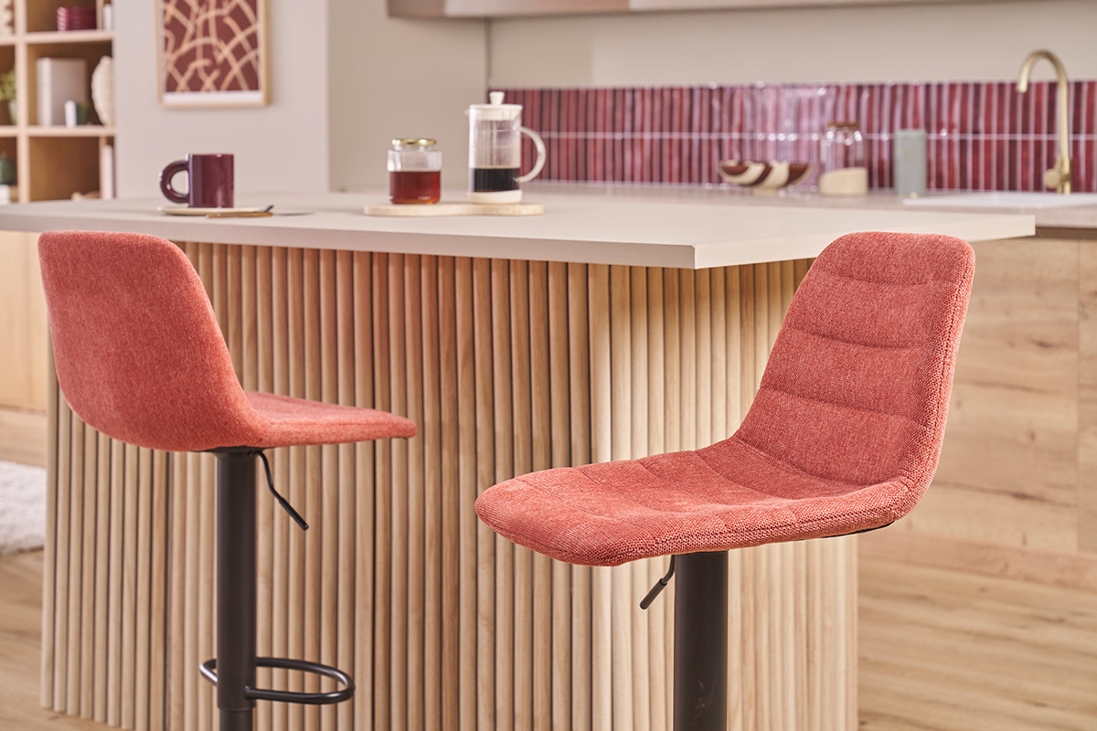 Deux tabourets de bar en tissu terracotta avec pieds en m�tal noir devant un �lot de cuisine.