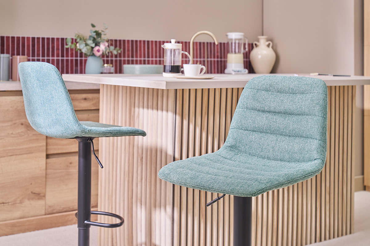 Deux tabourets de bar en tissu c�ladon devant un comptoir en bois.