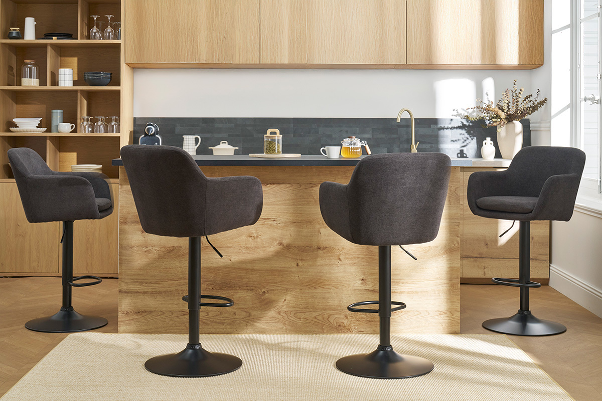 Quatre tabourets de bar gris fonc en tissu effet velours autour d'un lot de cuisine en bois.
