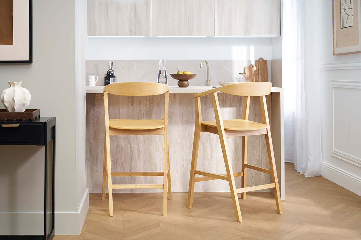 Tabourets de bar scandinaves en bois clair devant un lot de cuisine.