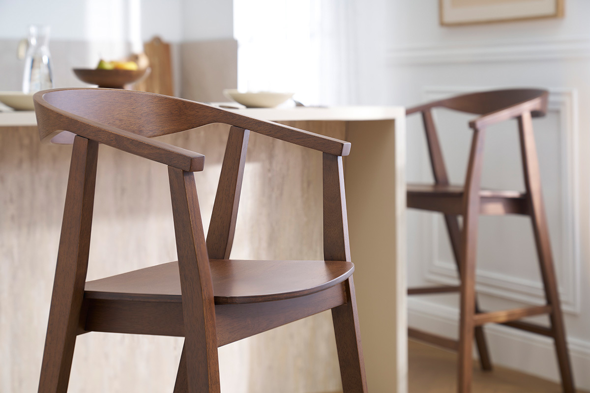 Deux tabourets de bar scandinaves en bois fonc vue de ct prs d'un lot de cuisine.