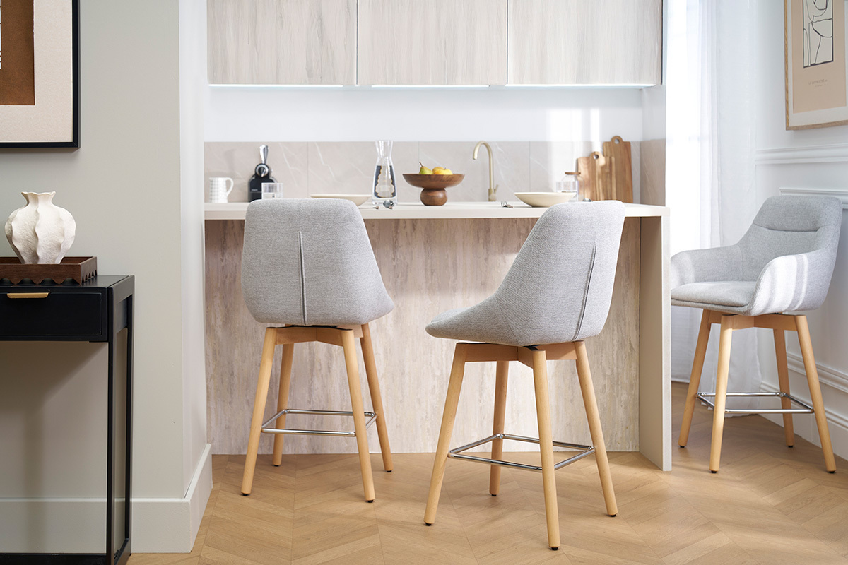 Tabourets de bar scandinaves pivotants gris clair et bois clair, vue de dos, dans une cuisine moderne.