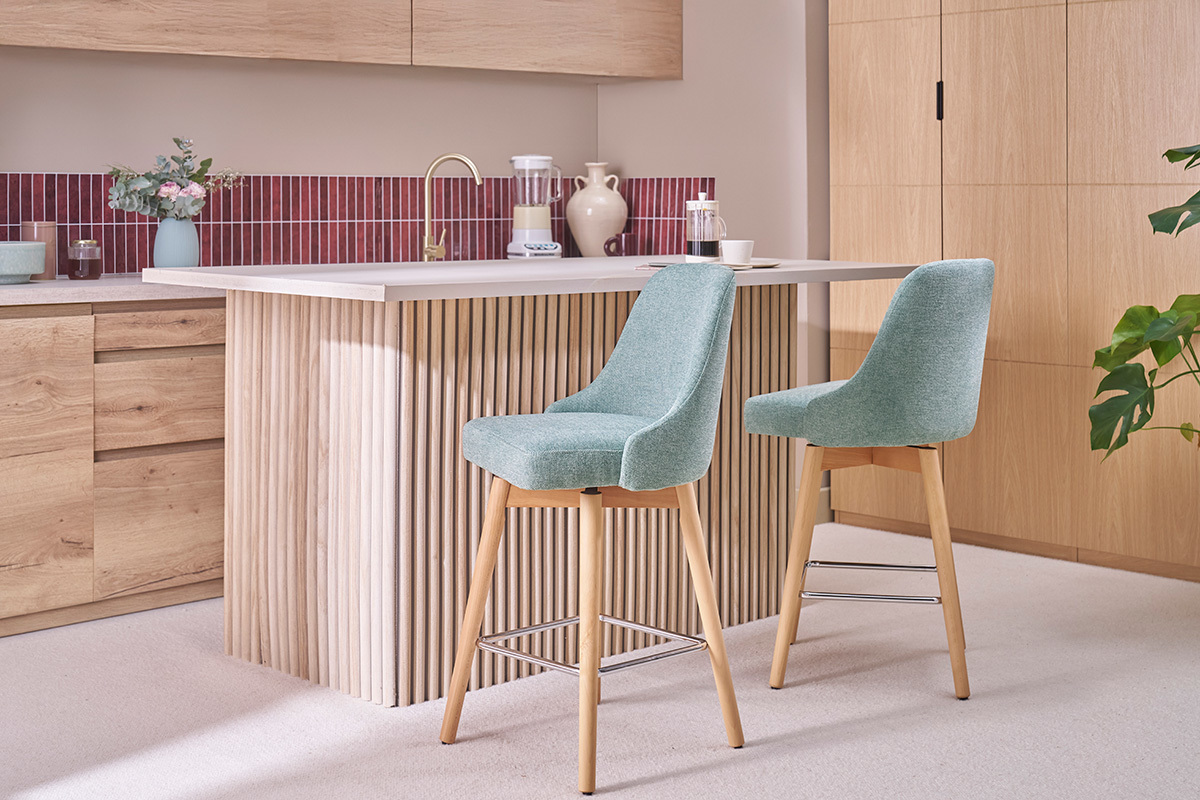 Deux tabourets de bar verts et en bois devant un comptoir de cuisine.