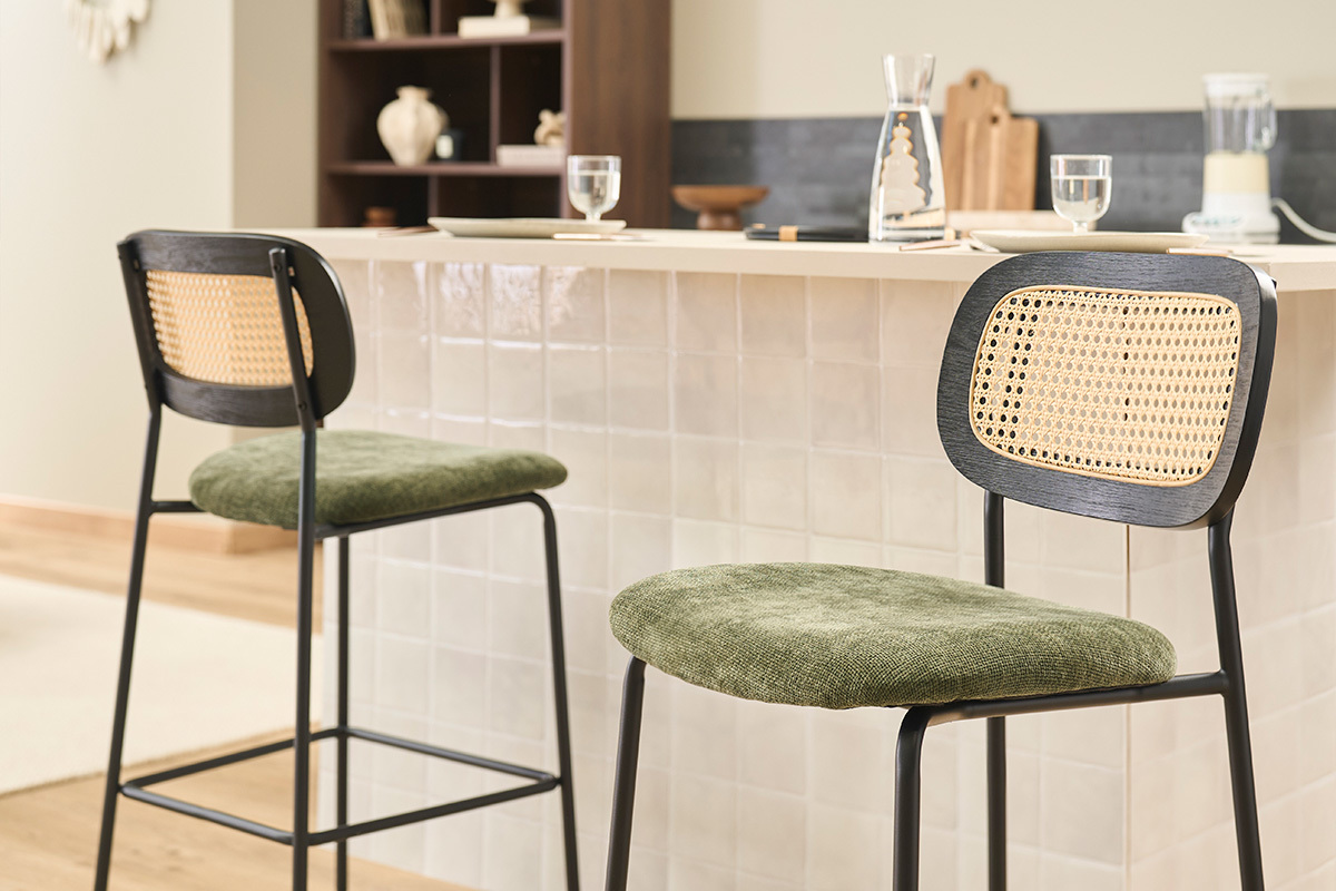Deux tabourets MIRANDA en velours vert et cann� devant un bar.