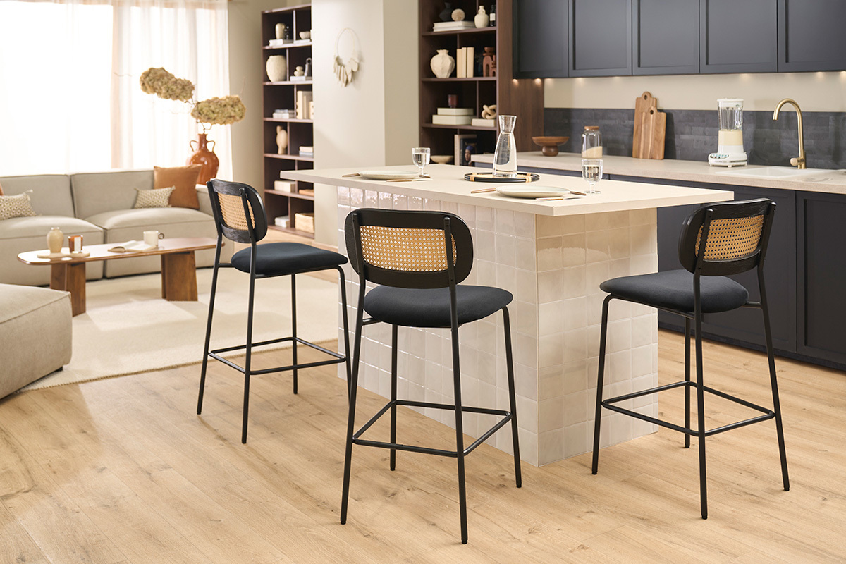 Tabourets en velours noir et cannage rotin pr�s d'un �lot de cuisine moderne.