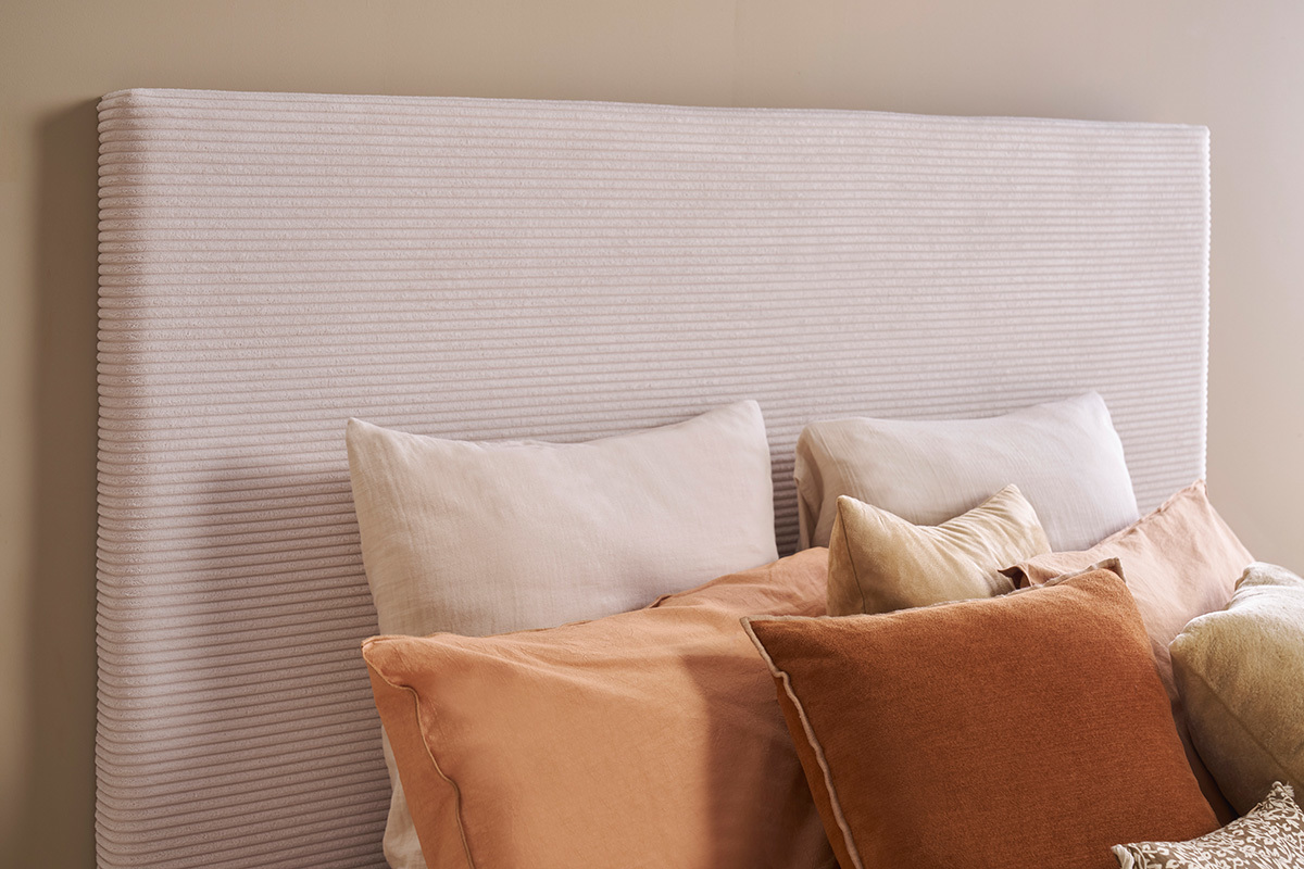Tte de lit en velours ctel beige YOLANDA avec oreillers, vue en angle.