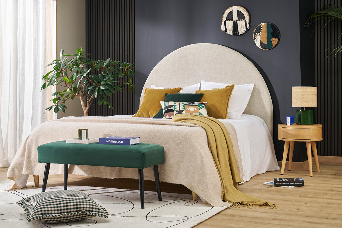 Chambre avec tte de lit ronde beige, coussins, table d'appoint et dcoration murale.
